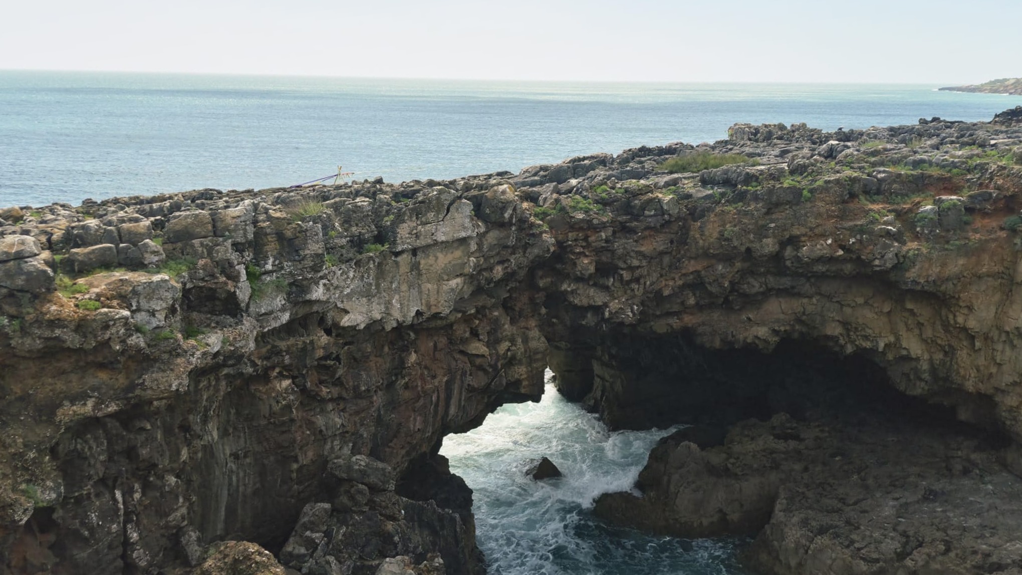 O arco natural da Boca do Inferno com ondas ao fundo